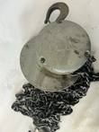 Gray Yale chain hoist with the name on its bolted cover, top hook and loops of load chain below
