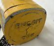 Cast Budgit 1 Ton name on the end cover of a yellow chain hoist, with worn paint at the edge