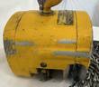 Side of a yellow Budgit hoist body with a data plate, top hook stem and worn paint