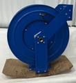 Blue Coxreels spring hose reel with angled guide arm and center inlet, on a cardboard base