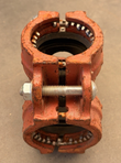 Red grooved coupling seen from the side, bolt and nut across the housing with gasket visible