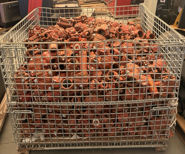 Wire basket bin filled with red ductile iron pipe couplings and fittings