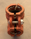 Red grooved pipe coupling, side view of the bolt and nut with gripping teeth showing at both ends
