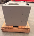 Gray ALCAD charger enclosure on a wood pallet, side panel with drilled holes