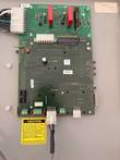 Green circuit board inside the charger door with yellow caution label and terminal blocks