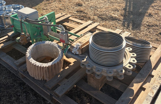 Green hydraulic actuator on a stainless bellows gate valve, plus a wrapped spare bellows, on a wood pallet