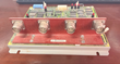 GE control board with red faceplate and four round connectors, mounted in a gray metal tray