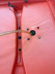 Inside of the red cart lid with amber beverage line through a hole and mounting bolts