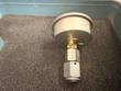 Back of a pressure gauge with brass fitting and steel hex adapter in the case foam