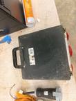 Scuffed black back of the Brennenstuhl box with handle and label, a plug and cord on the table below
