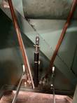Black dampening cylinder and steel linkage rods under the saw base