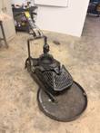 Black propane floor buffer with round deck, engine guard and handle on a concrete shop floor