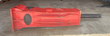Red hydraulic breaker lying on its side with the chisel to the right