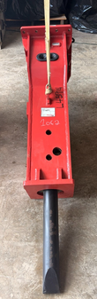 Red Connect hydraulic breaker standing upright on a lifting strap, chisel pointing down