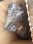 Concrete grinder wrapped in plastic inside an open wooden shipping crate, switches and warning label showing