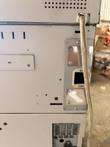 Side panel of the cash recycler with a cable plugged into a metal port plate and a vent below