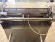 Close view of the rollers and stainless catch tray of a meat tenderizer, power cord looped in front