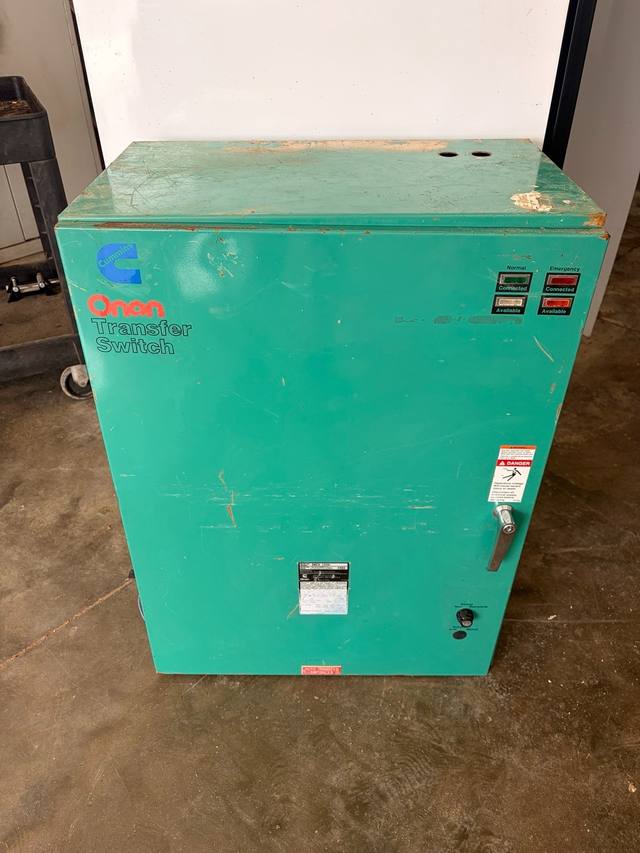 Teal Cummins Onan automatic transfer switch enclosure, front view with indicator lights, handle and data plate