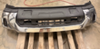 Chrome front bumper assembly with black upper trim and grille opening, on a pallet