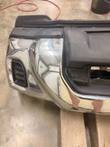 Left corner of the chrome front bumper showing the vent opening