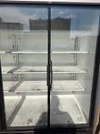 Two glass cooler doors with black frames and a black handle, empty white shelves inside