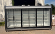 Six-door glass merchandiser cooler, front view with empty white shelves, black door frames and gray canopy