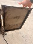 Inside face of the open smoker door, soot-stained, held by a hand