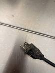 Black power plug and cord resting on the stainless smoker panel