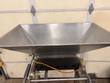 Large stainless steel hopper from above, black outlet block with five round holes and air cylinders below