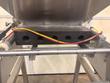 Black manifold block with five round outlet holes under the stainless hopper, air lines above