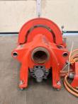 Orange powered pipe roll grooving machine from the front, with pipe bore, gear guard, motor and foot pedal box