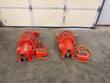 Two orange pipe grooving machines side by side on a concrete floor, each with its own foot switch and cord