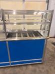 Three-quarter front view of the right half of the Atlas Metal cold food counter and its glass sneeze guard