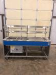 Rear open-frame view of the Atlas Metal cold food counter showing the compressor, power cords and casters
