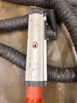 Handheld induction transformer body of the EFD MINAC system with an orange-taped hose connection