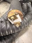 End of a handheld induction transformer with brass clamps, bolts and white insulator on a copper-colored ring