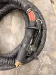 Handheld induction transformer with red leads, black handle, brass end and braided cooling hose