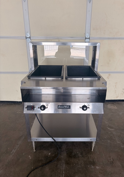 Stainless two-well steam table with raised sneeze guard, two temperature dials and lower shelf