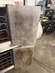 Stained doors swung open on a stacked convection oven, wire racks visible inside both cavities