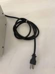 Black power cord coiled with a cable tie and three-prong plug beside the cream pump drive housing