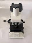 Front of white VistaVision trinocular microscope with camera port on top and power cord at left