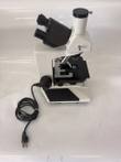 White trinocular microscope with binocular head, mechanical stage and power cord coiled beside the base
