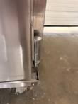 Chrome door hinge at the lower corner of the Winston CVap cabinet, with the base tray edge and a caster below