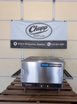Lincoln Impinger conveyor oven on legs on a wooden pallet, conveyor belt out both sides, control knobs on front