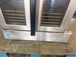 Two glass doors of a stainless convection oven with five racks each, Energy Star label on base, on a pallet