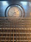Convection fan guard on the oven back wall above wire racks with light surface rust