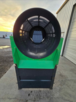 End view of the green trommel screener: black drum opening with mesh inside, on black steel legs