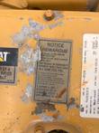 Worn Caterpillar EPA and CARB certification notice label in English and French on the valve cover