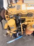 Front of the Caterpillar engine: fan pulley, yellow oil filter canister and valve cover with labels