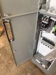 Open gray motor control center door with handle, starter and motor protectors visible inside the cabinet